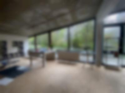 Workspace with large windows. There is a desk, a shelf, a smaller round table and large sheets of paper or photographic print on the floor. On the wall, hang several photographic prints showing the same flower.