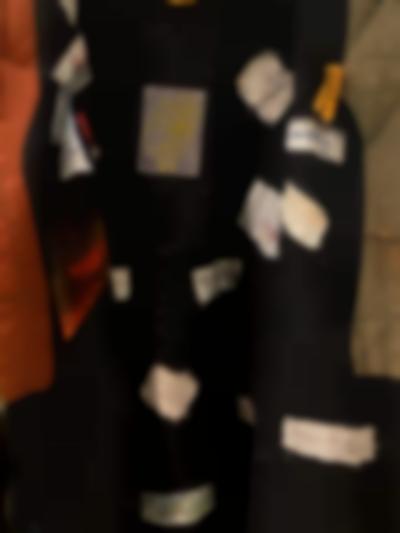 Detail of a thick piece of fabric to which small patches of other fabric have been attached. These patches have drawings or writing on them.